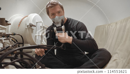 Military man receiving treatment in industrial hyperbaric chamber 114551621