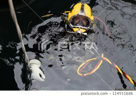 Commercial diver in Kirby Morgan helmet on water surface 114551686