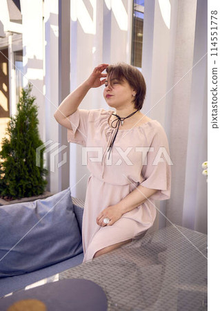 medium sized woman in peach fuzz dress with glass of water in restaurant medium sized woman in peach fuzz dress with glass of water in restaurant 114551778