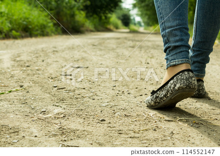 The girl goes on a dirt road through the trees The girl goes on a dirt road through the trees 114552147