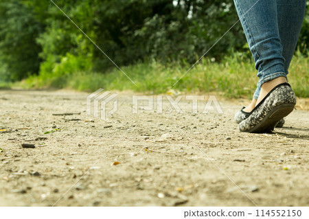 The girl goes on a dirt road through the trees 114552150