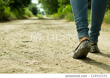 The girl goes on a dirt road through the trees The girl goes on a dirt road through the trees 114552151