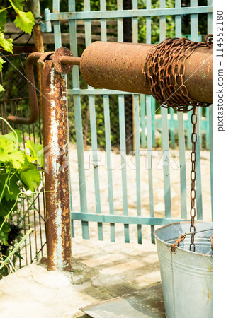 Well water and a bucket on a chain 114552180