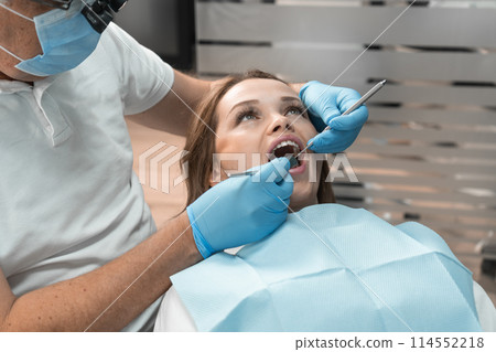 The dentist in clinic conducts professional treatment patient's teeth using advanced methods and technologies. Her attention to detail and specialized skills ensure effective and painless treatment. The dentist in clinic conducts professional treatment patient's teeth using advanced methods and technologies. Her attention to detail and specialized skills ensure effective and painless treatment. 114552218