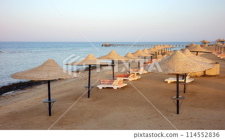 Beach with sun loungers and umbrellas at sunset, Marsa Alam region, Egypt. Beach with sun loungers and umbrellas at sunset, Marsa Alam region, Egypt. 114552836