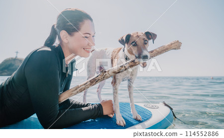 Sea woman sup. Silhouette of happy positive young woman with her dog, surfing on SUP board through calm water surface. Idyllic sunset. Active lifestyle at sea or river. Summer vacation with pets. 114552886