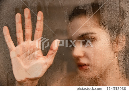 Woman touching steamy shower glass with hand 114552988