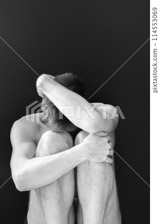 Man sitting in fear covering his face 114553069