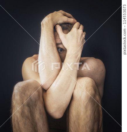 Man sitting in fear covering his face 114553073