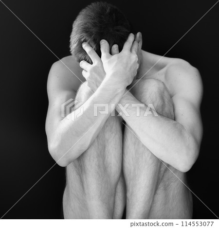 Man sitting in fear covering his face 114553077