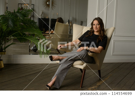 A psychologist girl in a business style poses in an interior photo studio. A psychologist girl in a business style poses in an interior photo studio. 114554699