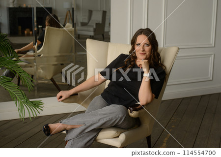 A psychologist girl in a business style poses in an interior photo studio. 114554700
