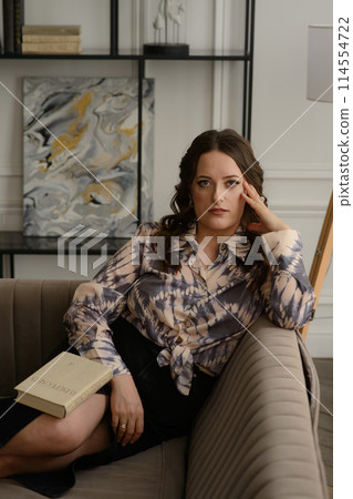 A psychologist girl in a business style poses in an interior photo studio. 114554722