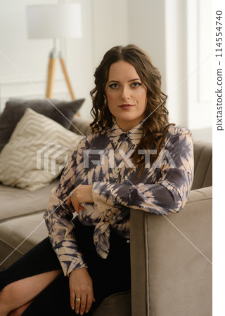 A psychologist girl in a business style poses in an interior photo studio. A psychologist girl in a business style poses in an interior photo studio. 114554740