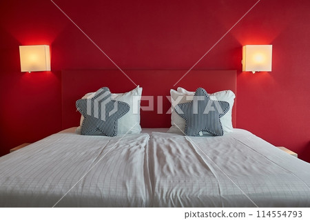 Hotel bed with white sheets, red wall 114554793