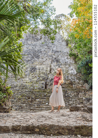 Woman tourist at Coba, Mexico. Ancient mayan city in Mexico. Coba is an archaeological area and a famous landmark of Yucatan Peninsula. Cloudy sky over a pyramid in Mexico 114555102