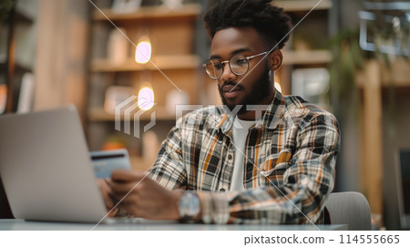 Focused African American man using credit card for online shopping modern workspace 114555665
