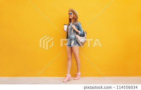 Beautiful stylish happy young woman with cup of coffee wearing summer hat on yellow background Beautiful stylish happy young woman with cup of coffee wearing summer hat on yellow background 114556034