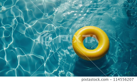 A bright yellow ring floats gently on the surface of a clear blue pool, creating ripples in the water 114556207