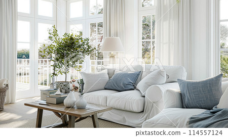 Interior of a living room with white walls, sofa and cushions. Sitting room in coastal cottage with sea view. Luxury lounge room 114557124
