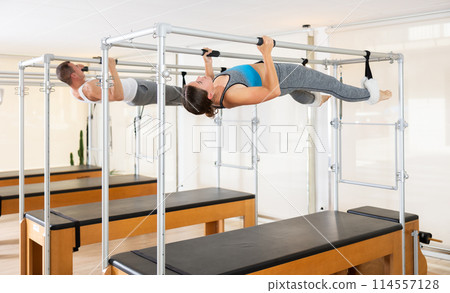 Girl performing inverted hanging pull-ups on Pilates trapeze table 114557128