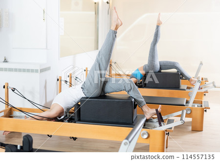 Man performing pilates exercises on reformer with box at group workout Man performing pilates exercises on reformer with box at group workout 114557135