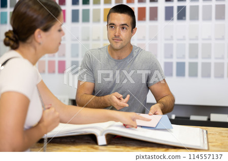 Polite salesman of painting supply store consulting female client Polite salesman of painting supply store consulting female client 114557137