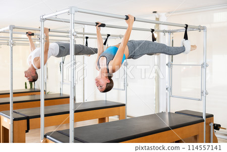 Girl and man do pilates suspended on special sports equipment 114557141