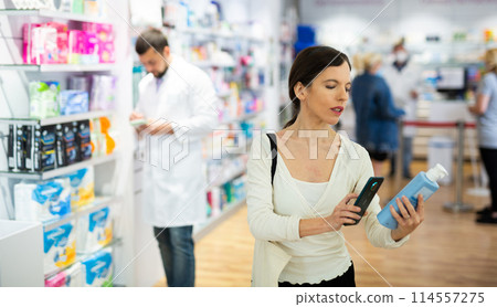 Female customer scans barcode on a medicine box using phone Female customer scans barcode on a medicine box using phone 114557275