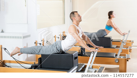 Man performing exercises on Pilates reformer with box in studio Man performing exercises on Pilates reformer with box in studio 114557277
