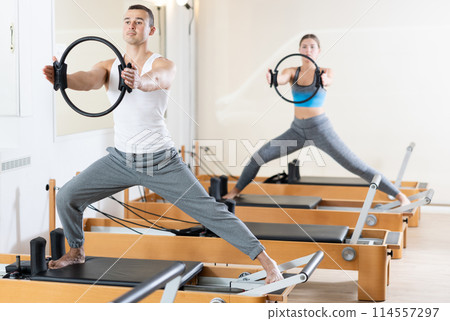 Girl and man exercising with pilates rings on reformer in fitness studio. Healthy lifestyle concept Girl and man exercising with pilates rings on reformer in fitness studio. Healthy lifestyle concept 114557297