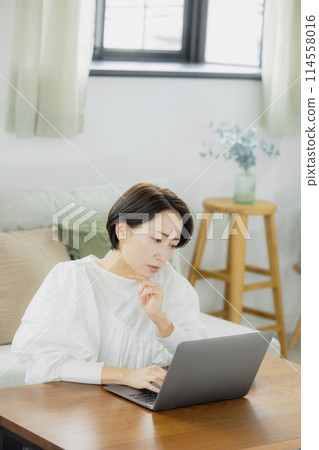 在客廳裡使用電腦的中年女人 114558016