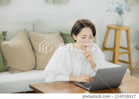 在客廳裡使用電腦的中年女人 在客廳裡使用電腦的中年女人 114558017