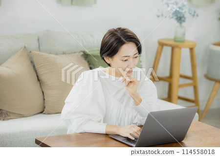 在客廳裡使用電腦的中年女人 在客廳裡使用電腦的中年女人 114558018