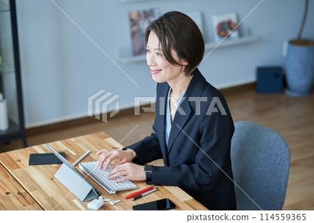 A woman in a suit sitting in front of a tablet PC 114559365