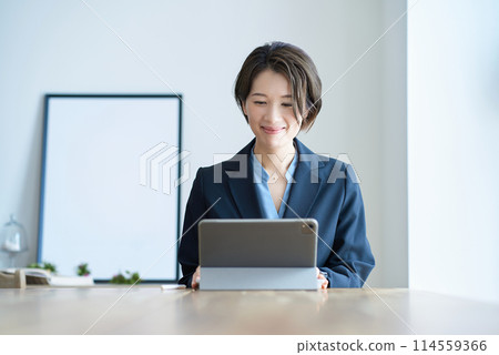 一個穿著西裝的女人坐在平板電腦前 114559366