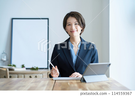 一個穿著西裝的女人坐在平板電腦前 114559367