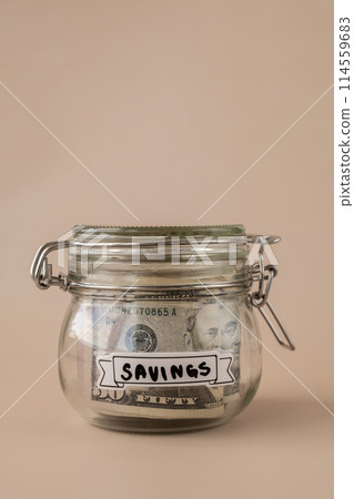 Glass jar full of American currency dollars cash banknote with text SAVINGS. Preparation saving money. Moderate consumption and economy 114559683