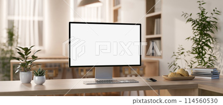 A computer mockup and objects are on a wooden table in a contemporary minimalist co-working space. 114560530