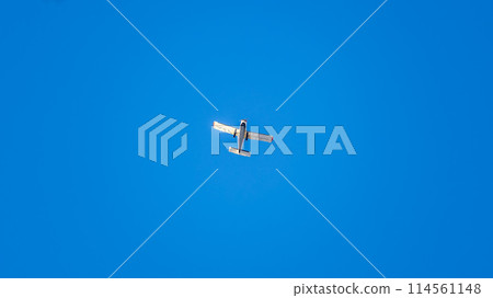 Small ultralight airplane with overhead wing and single propeller flying in sunset sky. 114561148