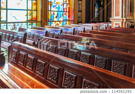 Empty wooden church benches of a Christian church. Blurry alter in the background. Selective focus. Concept of church service or empty churches. Empty wooden church benches of a Christian church. Blurry alter in the background. Selective focus. Concept of church service or empty churches. 114561291