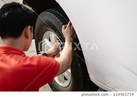 A man is inflating a tire with a tire inflator A man is inflating a tire with a tire inflator 114561714