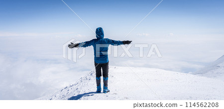 Mountaineer with crampons standing on a summit with clouds below him, Mount Ararat in Turkey 114562208