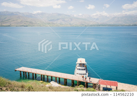 Tourists on the pier waiting for their boat with beautiful lake and mountains in backdrop, Turkey 114562210