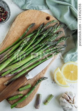 Fresh green asparagus lies on a wooden cutting board  114562656