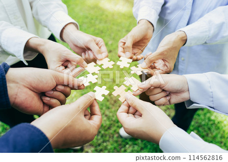 group of business people assembling jigsaw puzzle. The concept of cooperation, teamwork, help and support in business. group of business people assembling jigsaw puzzle. The concept of cooperation, teamwork, help and support in business. 114562816