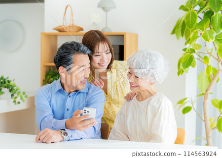 老夫婦和小孩在客廳看智慧型手機 114563924