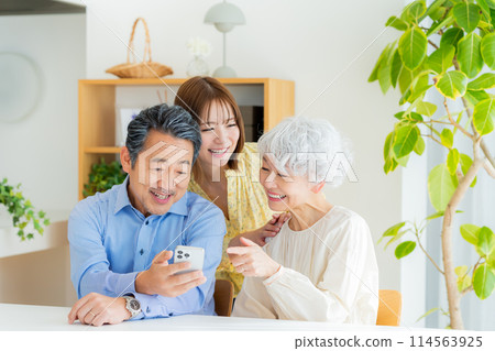 老夫婦和小孩在客廳看智慧型手機 114563925