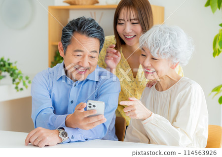 老夫婦和小孩在客廳看智慧型手機 114563926