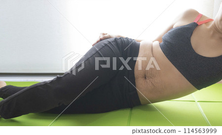 腹部有產後妊娠紋的女子在瑜珈墊上扭動臀部 114563999